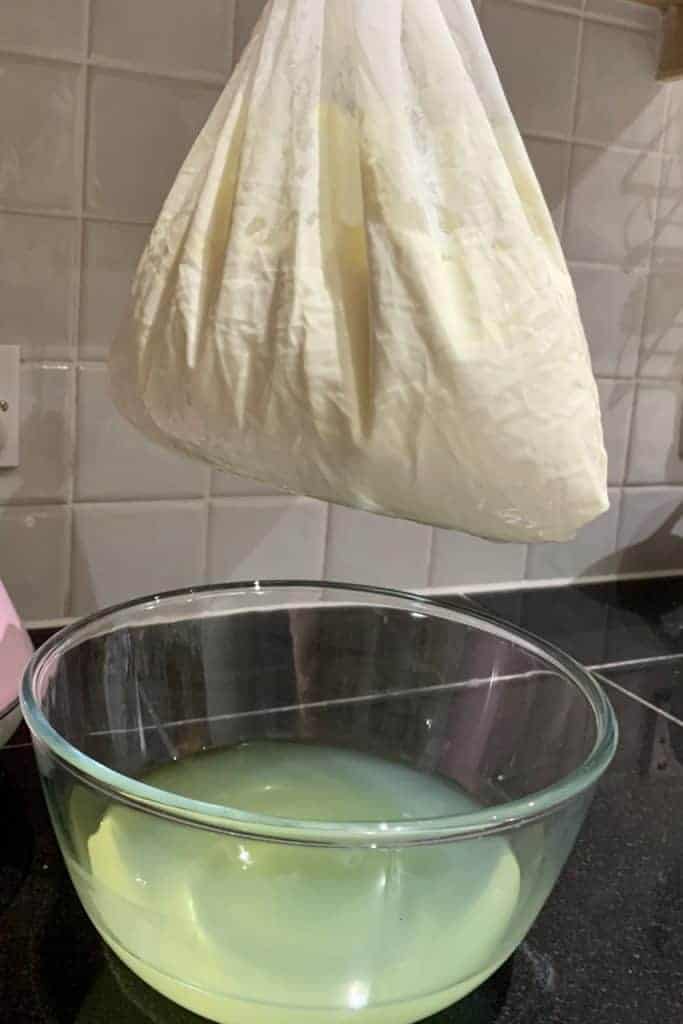 draining yogurt in a nut milk bag. bowl of whey underneath