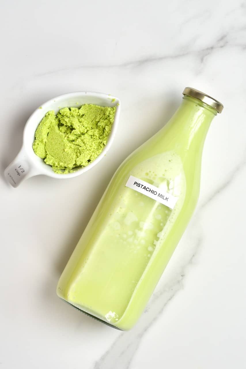 homemade pistachio in a bottle and some leftover nut meat - DIY pistachio milk recipe