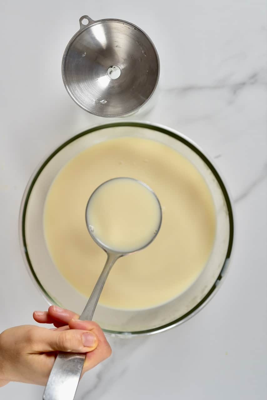 pouring soy milk in a bottle with a ladle