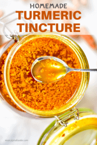 Top view of homemade turmeric tincture in a big jar with a spoonful of the tincture above it