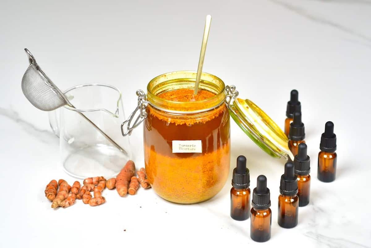 turmeric tincture, dropper bottle, turmeric root and strainer 
