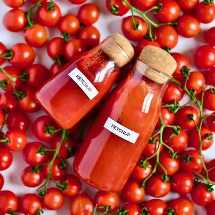 Two bottles of homemade ketchup and a bunch of tomatoes
