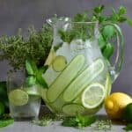Flavored water jug with herbs, lime and lemon and glass