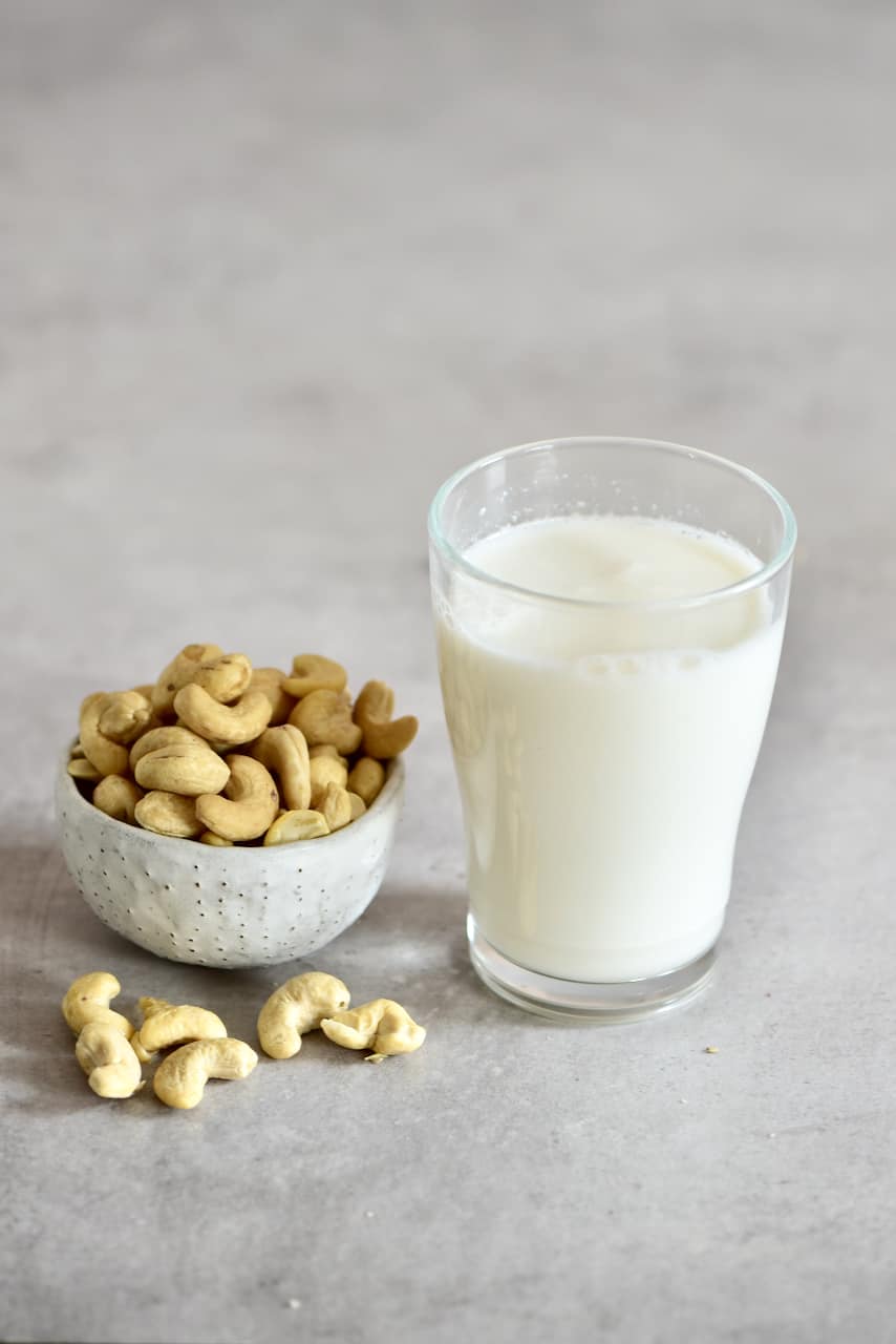 Cashew milk in a glass and a bowl of cashews