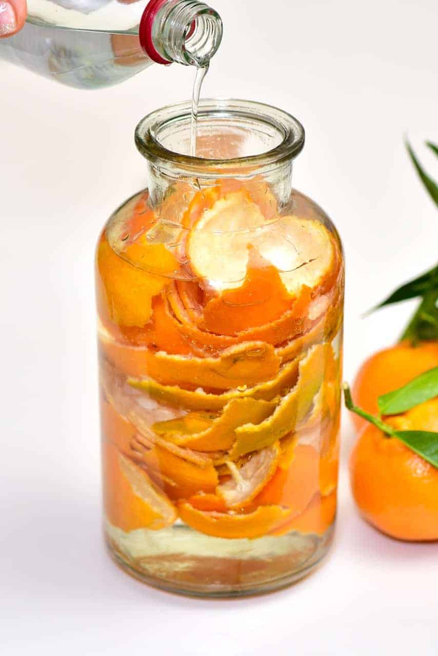 Filling up a jar with vinegar and citrus peel
