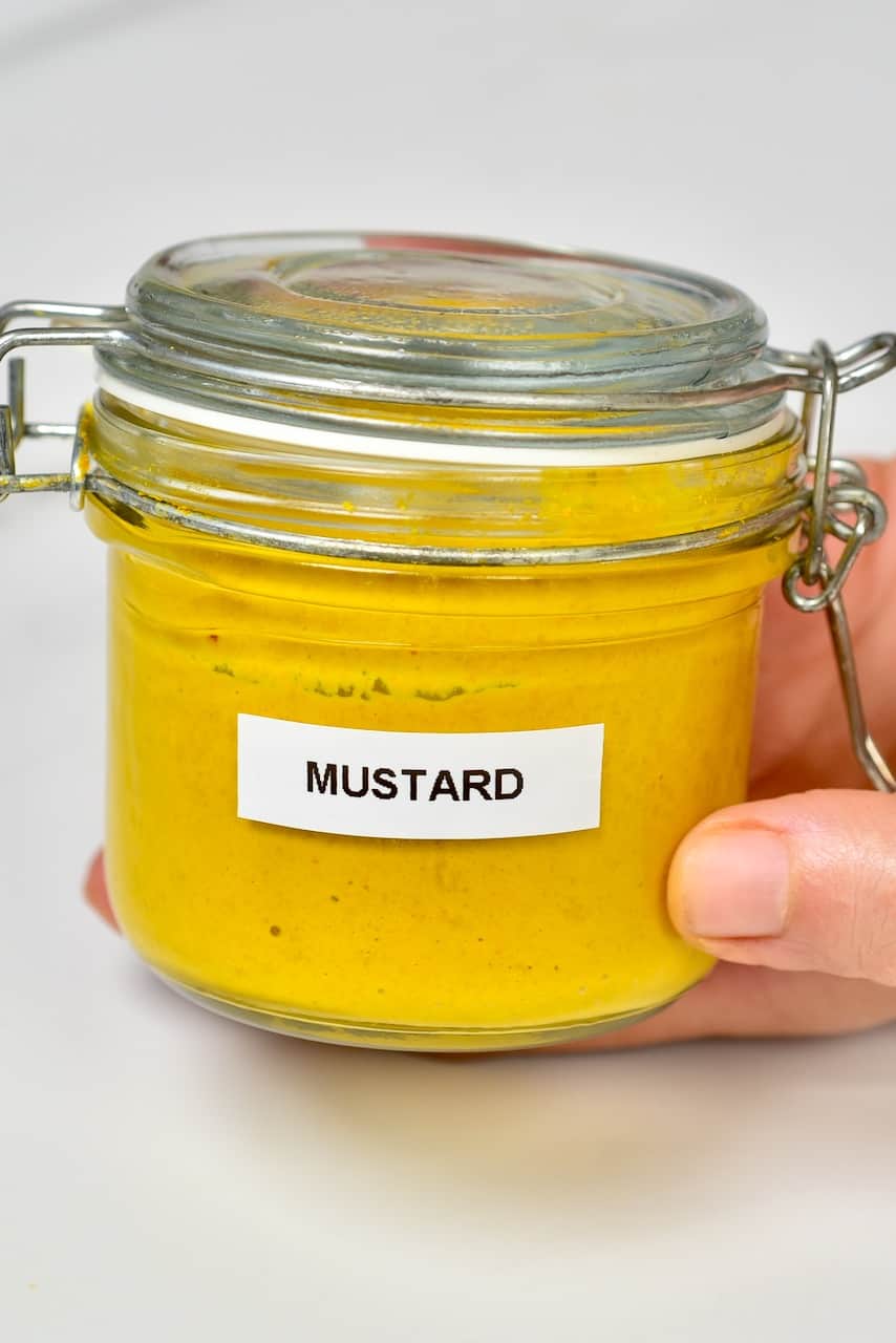 Hand holding jar with mustard
