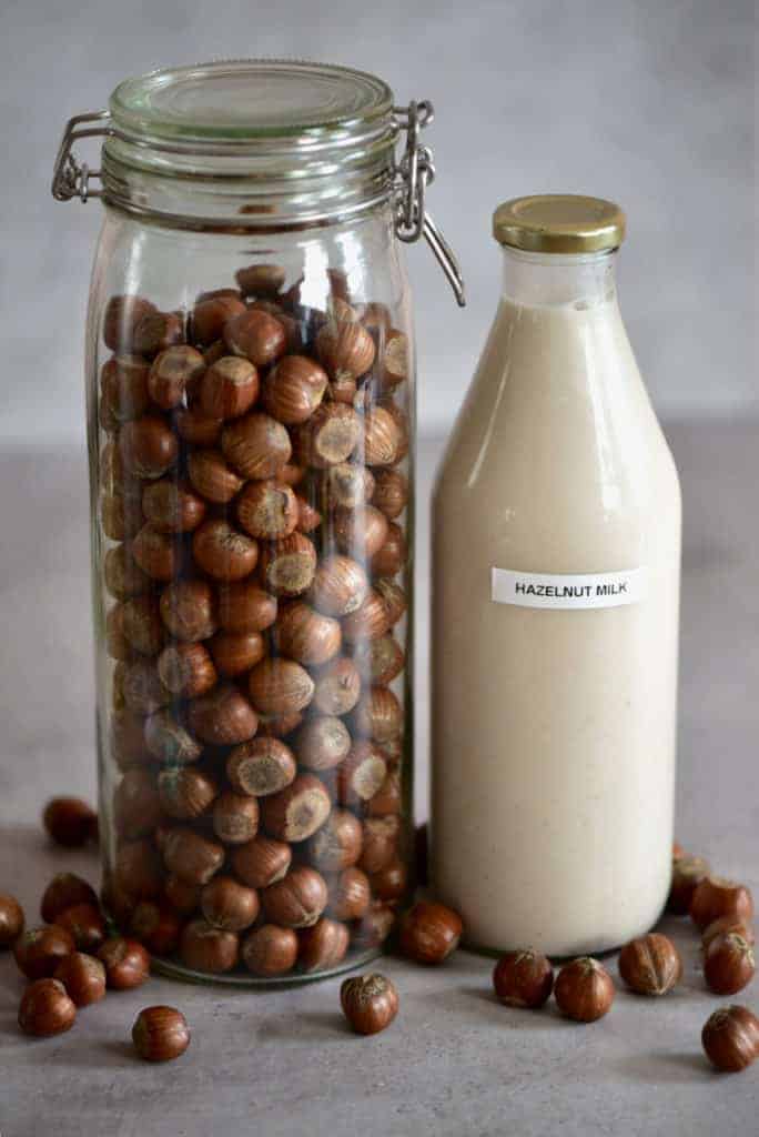 Hazelnut milk in a bottle and hazelnuts in a jar