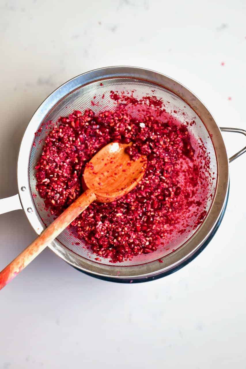 Mashed Pomegranate seeds in a sieve