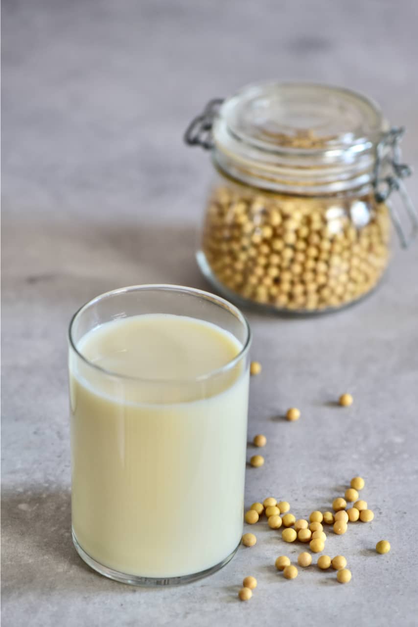 Soy milk in a glass with soy beans behind