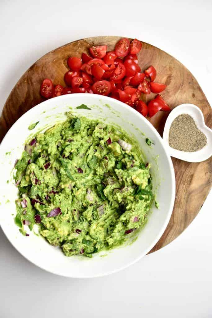 A bowl of guacamole and tomatoes