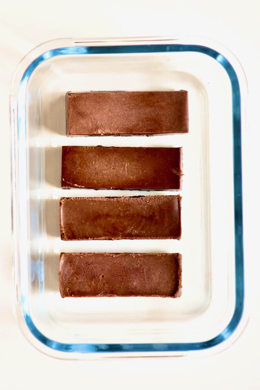 chocolate fudge bars inside a glass storage container
