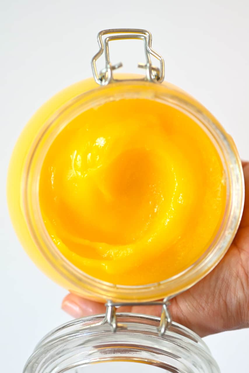 A jar with ghee held in a hand