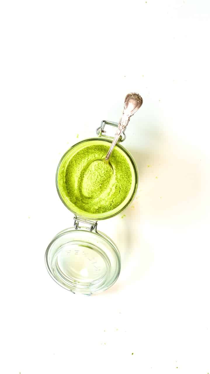 a spoon full of green pea powder on a jar