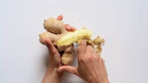 peeling off ginger root with a spoon