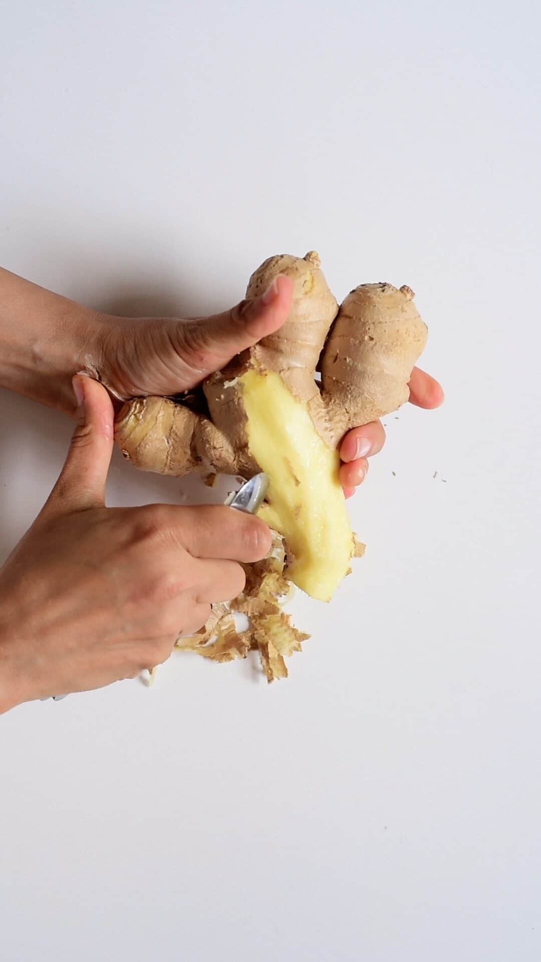 peeling off ginger root with a spoon vertical photo