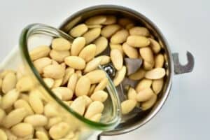 pouring blanched almonds into a grinder