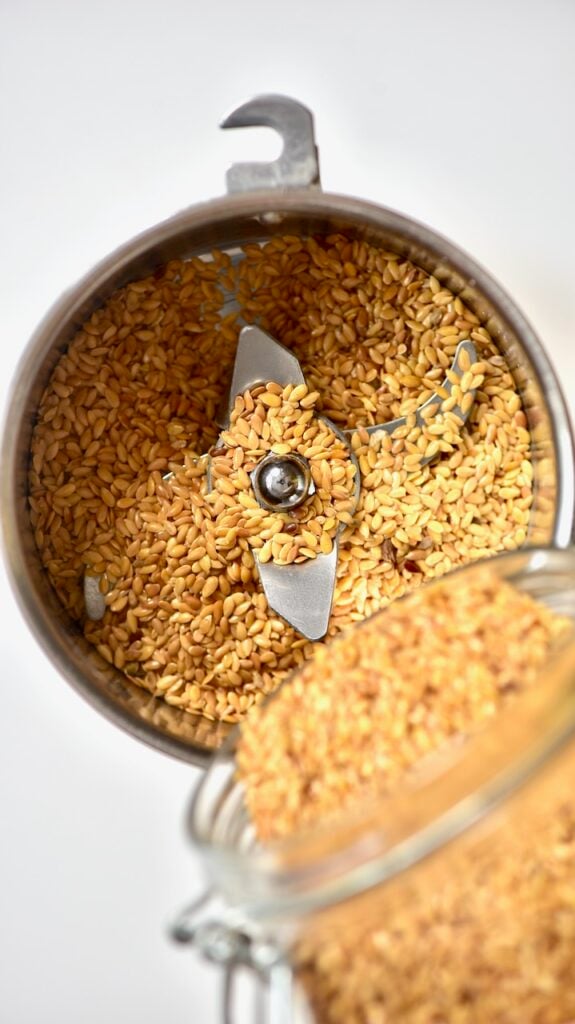 pouring golden Flaxseed into a spice grinder