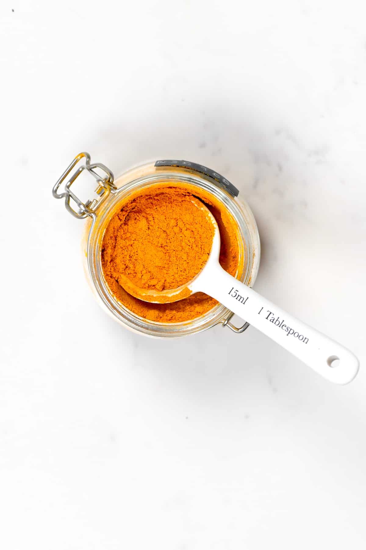 Turmeric mix in a jar with a measuring spoon