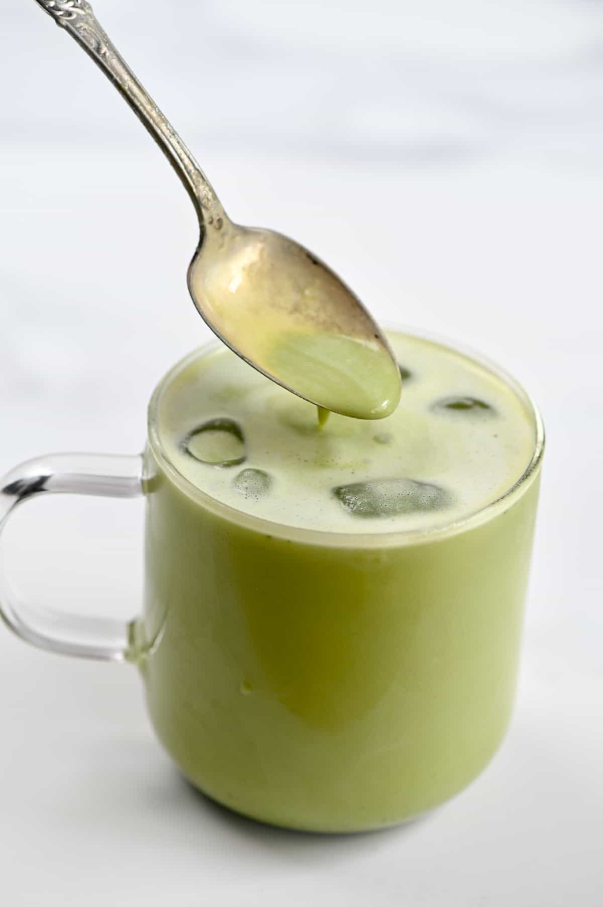 Iced matcha latte in a glass with a spoon
