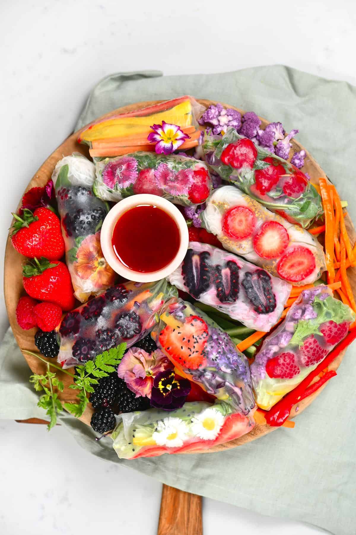 Spread of vegetable Rainbow rolls with dipping sauce on a wooden board