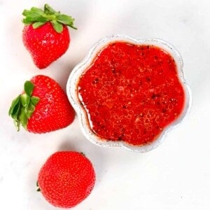 Strawberry Salad Dressing in a small bowl and three strawberries