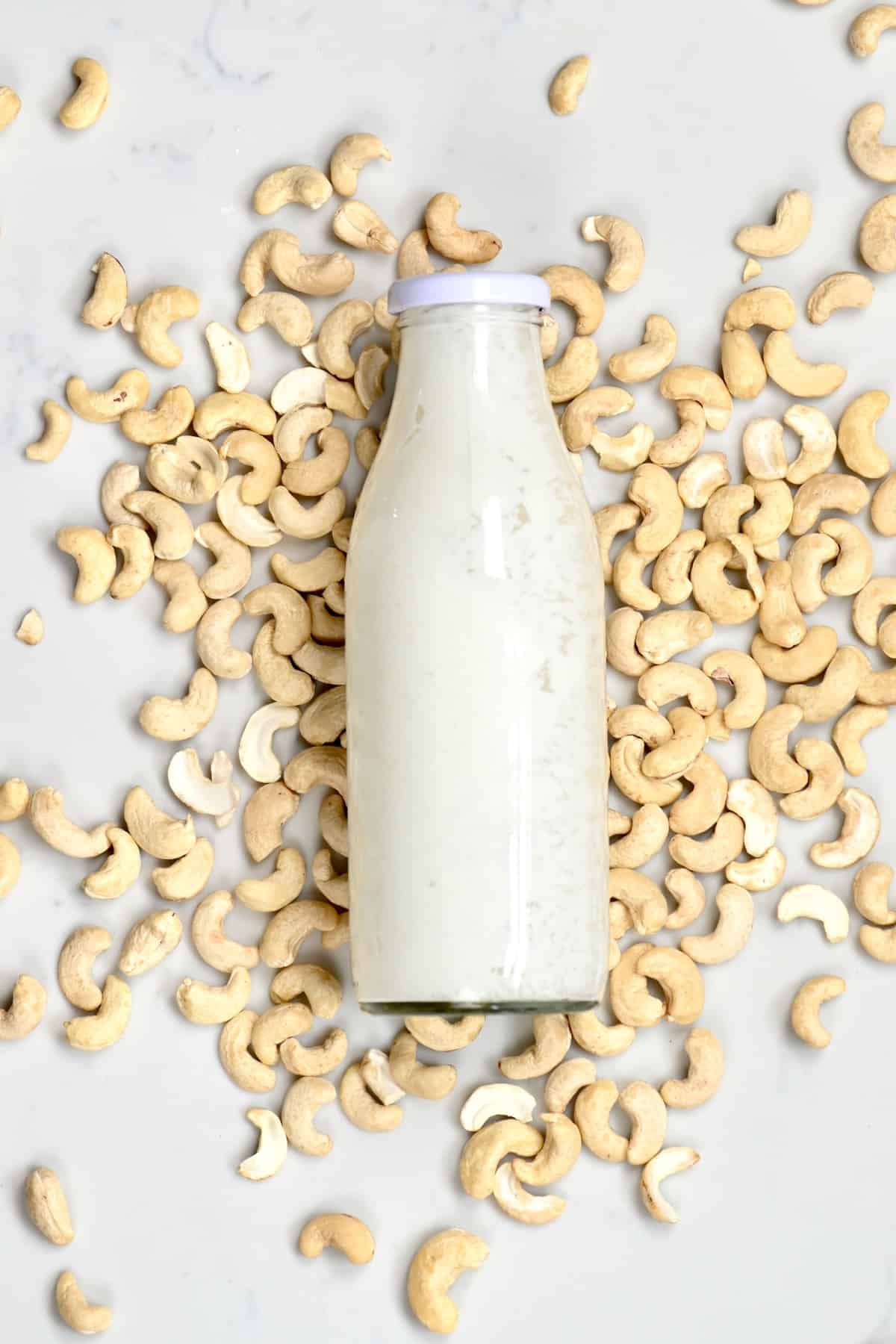 Cashew creamer in a glass bottle and cashew nuts next to it