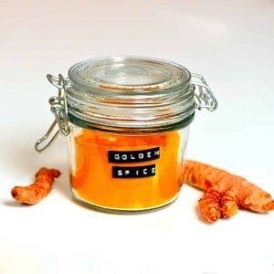 jar of golden spice mix with turmeric roots on the side