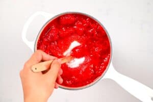 stirring sugar and mashed strawberries