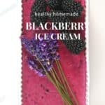 BLACKBERRY ICE CREAM IN a white tub topped with edible lavender and blackberries