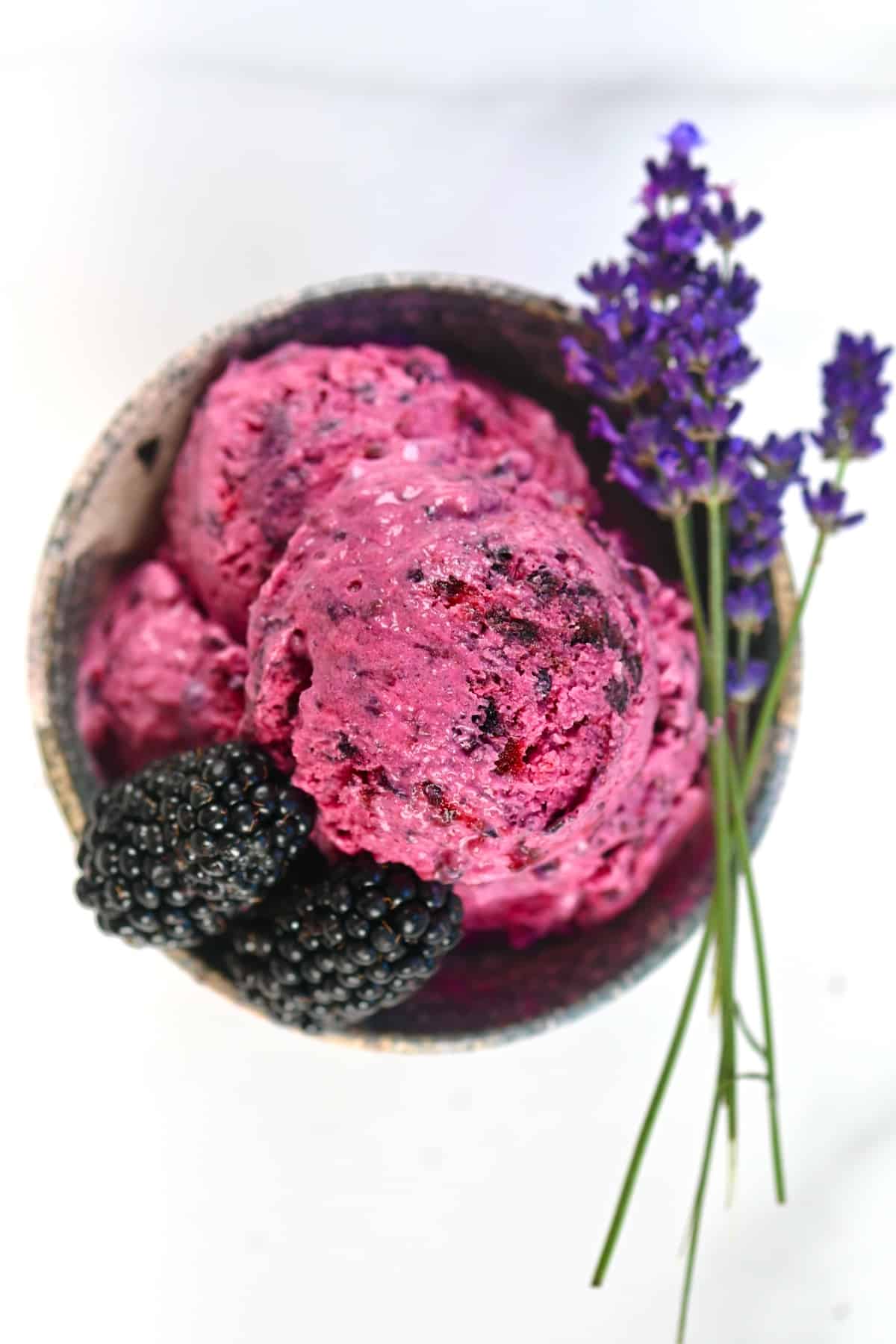 Blackberry Ice Cream scoops in a cup decorated with blackberries and lavender