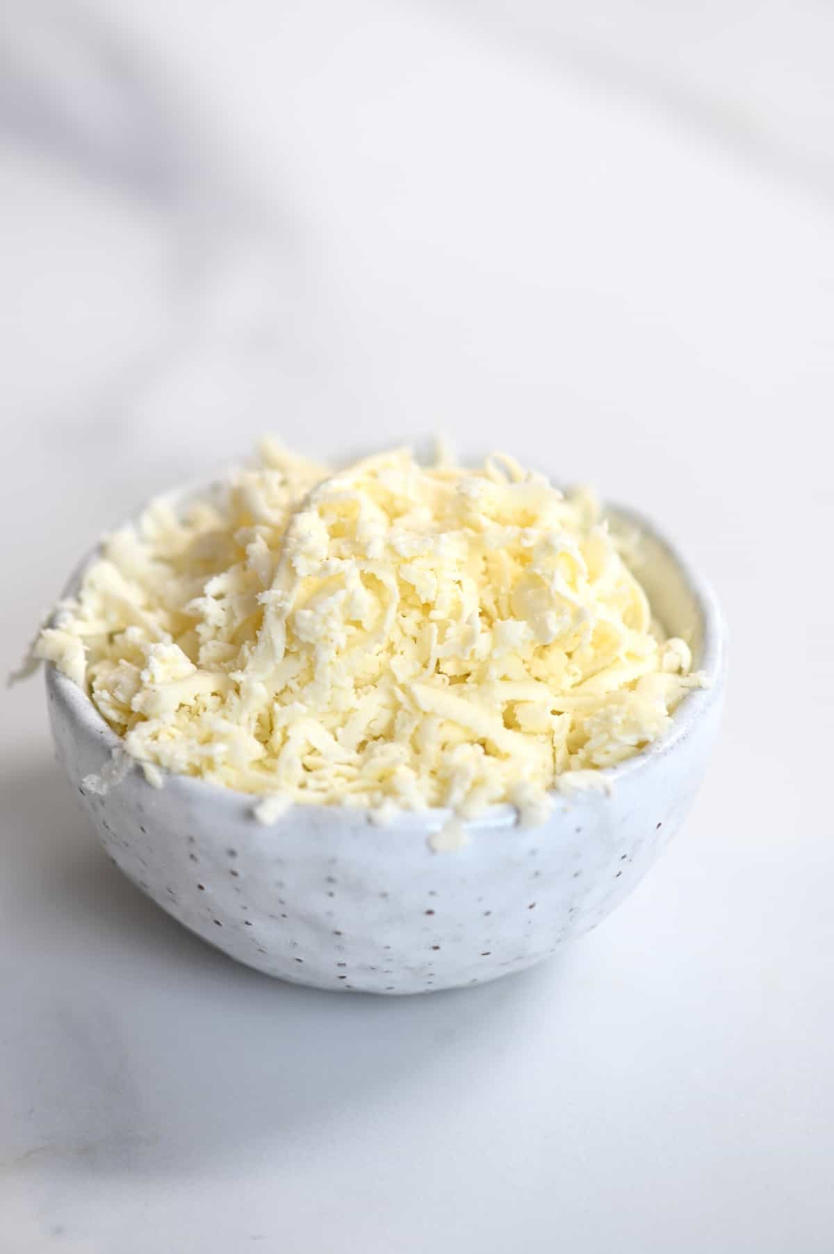 Homemade grated mozzarella cheese in a bowl