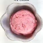 Raspberry ice cream scoop in a white cup