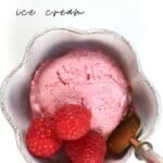 Raspberry ice cream scoop in a white flower shape cup with a spoon