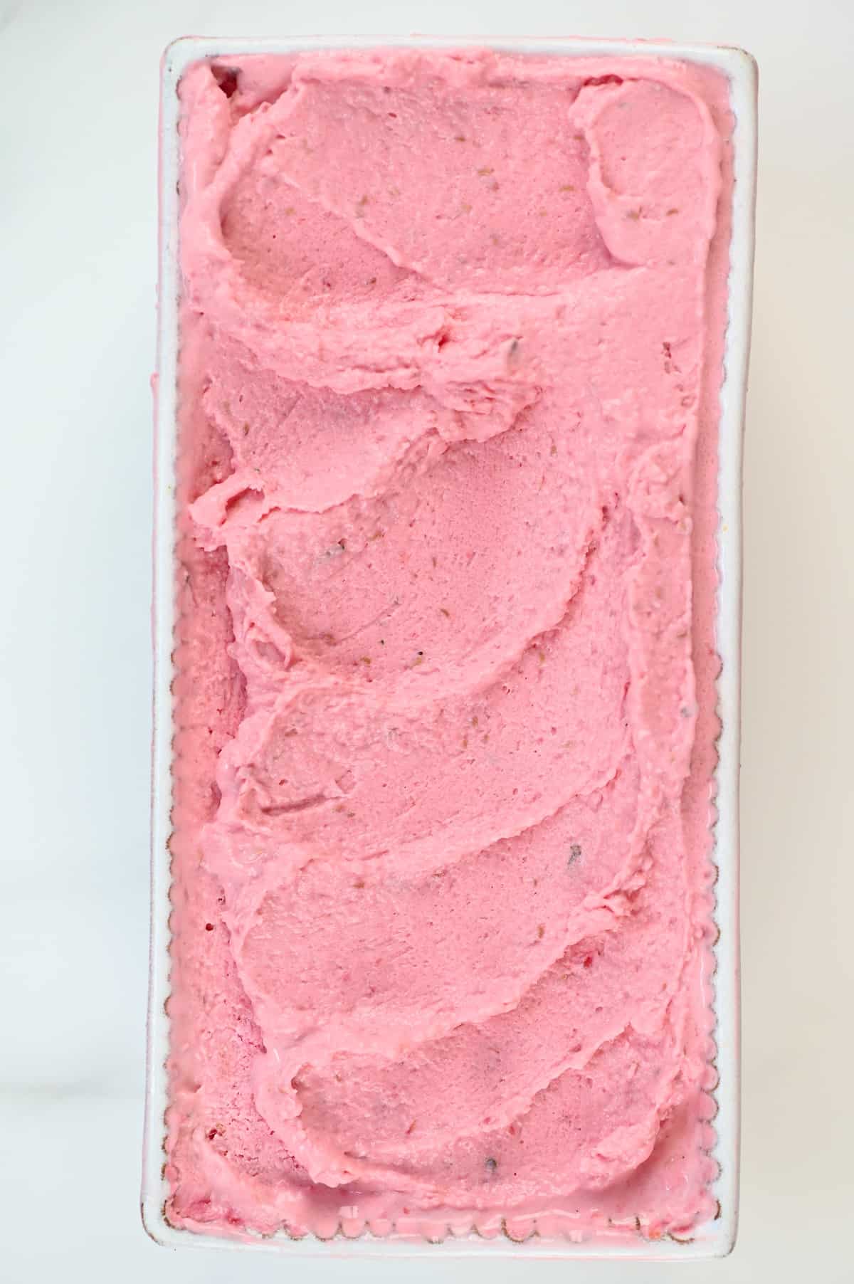 creamy homemade Raspberry Ice Cream in a glass tub