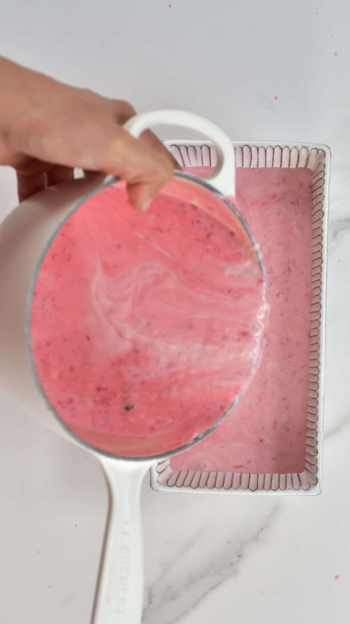 pouring Raspberry Ice Cream mixture into a glass freezer container