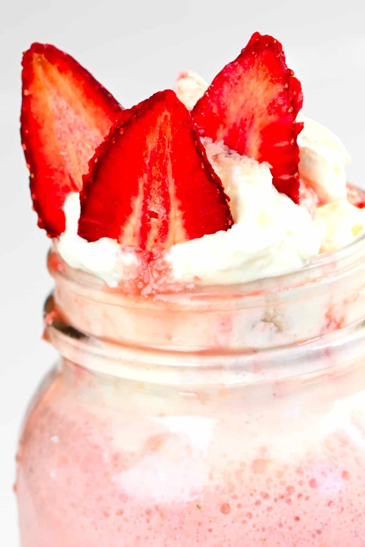 A close up of a strawberry Frappuccino topped with cream and strawberries