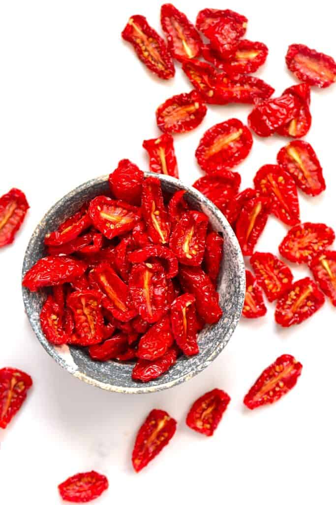Sun-dried tomatoes in a bowl and spilled around it