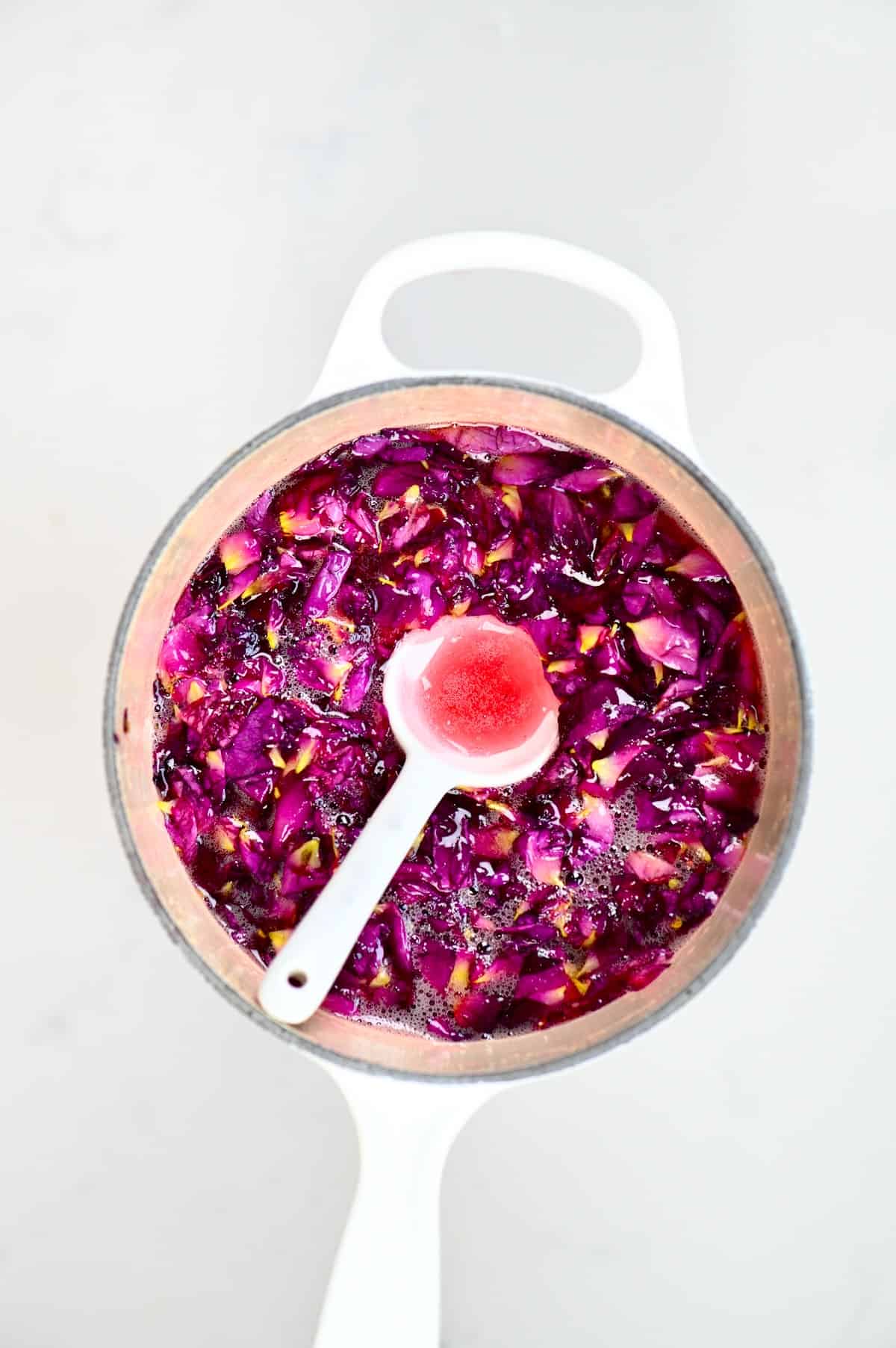 white spoon of Rose Jam inside a pot of jam