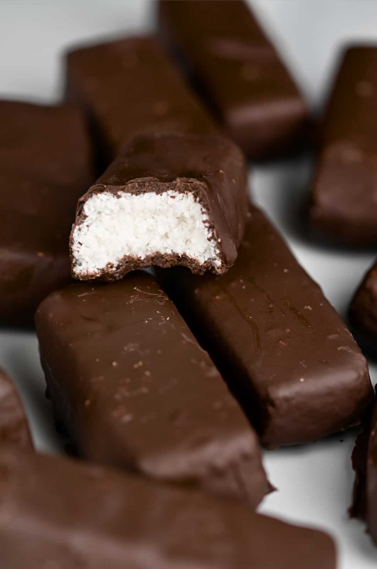 Some bounty bars on a flat surface and a half eaten bounty on top of them