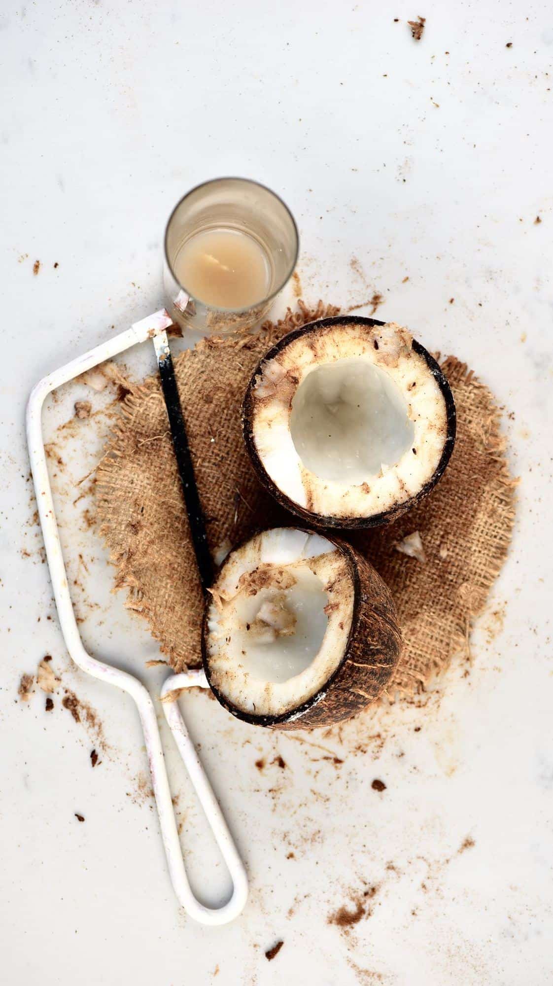 A coconut cut in two with a saw next to it