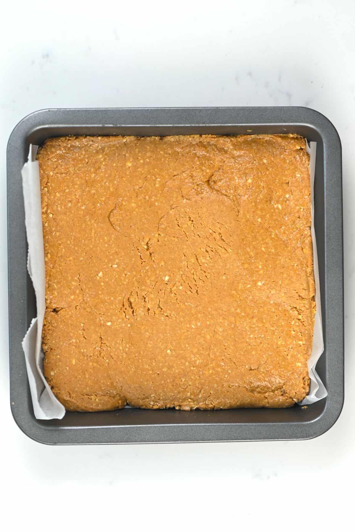 Peanut butter bar mixture spread in a tin tray