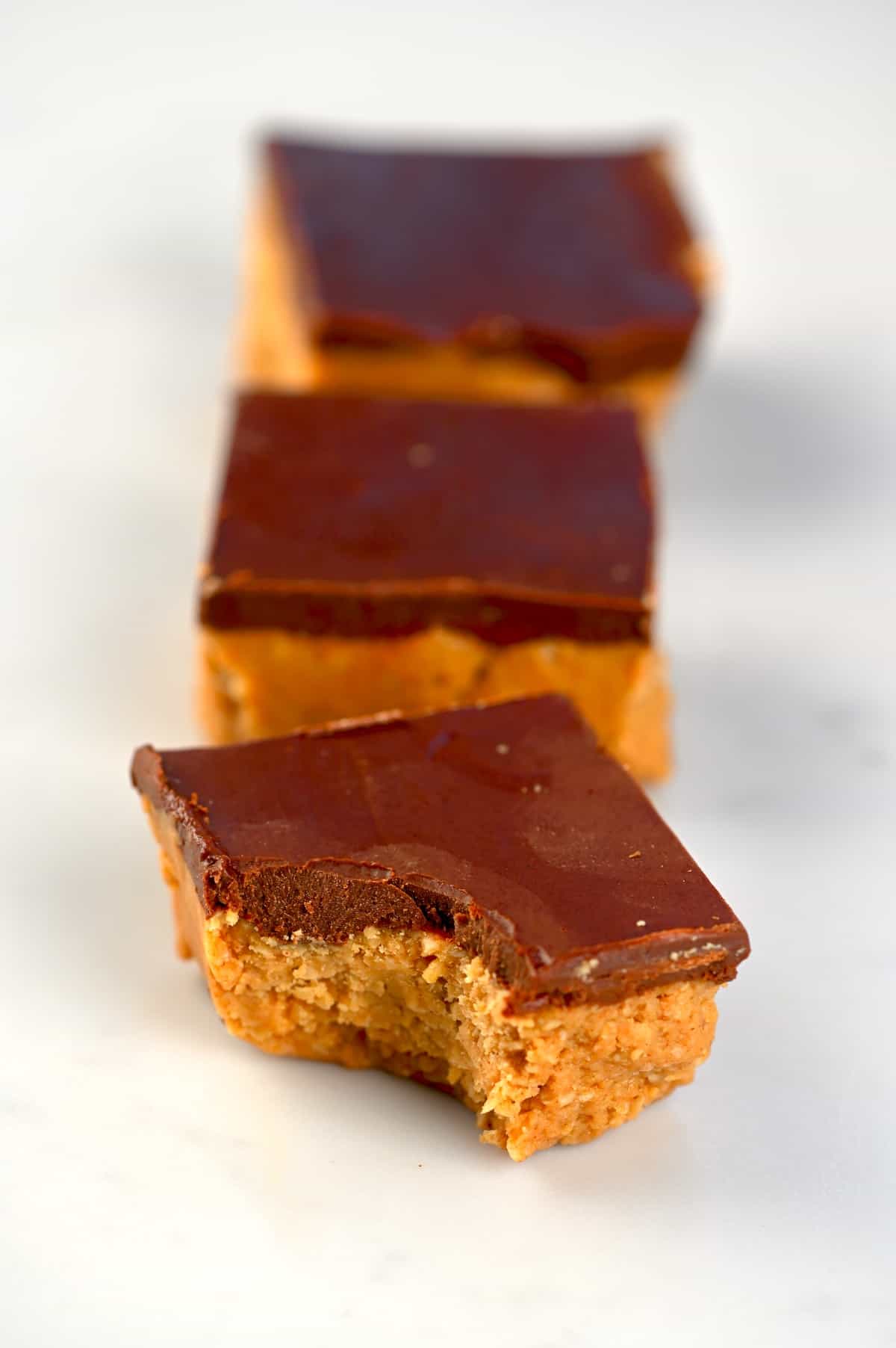 Three peanut butter bars with chocolate coating
