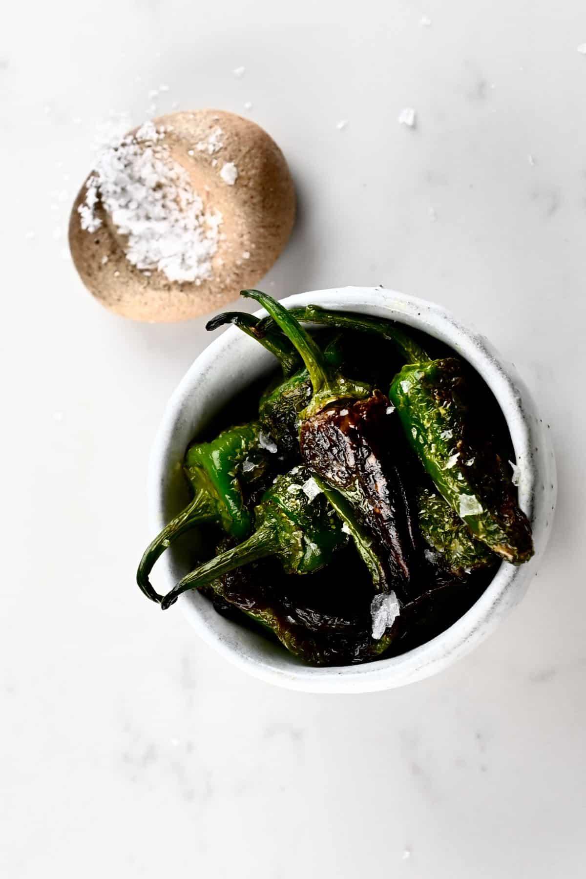 Padron peppers in a small bowl and salt on the side