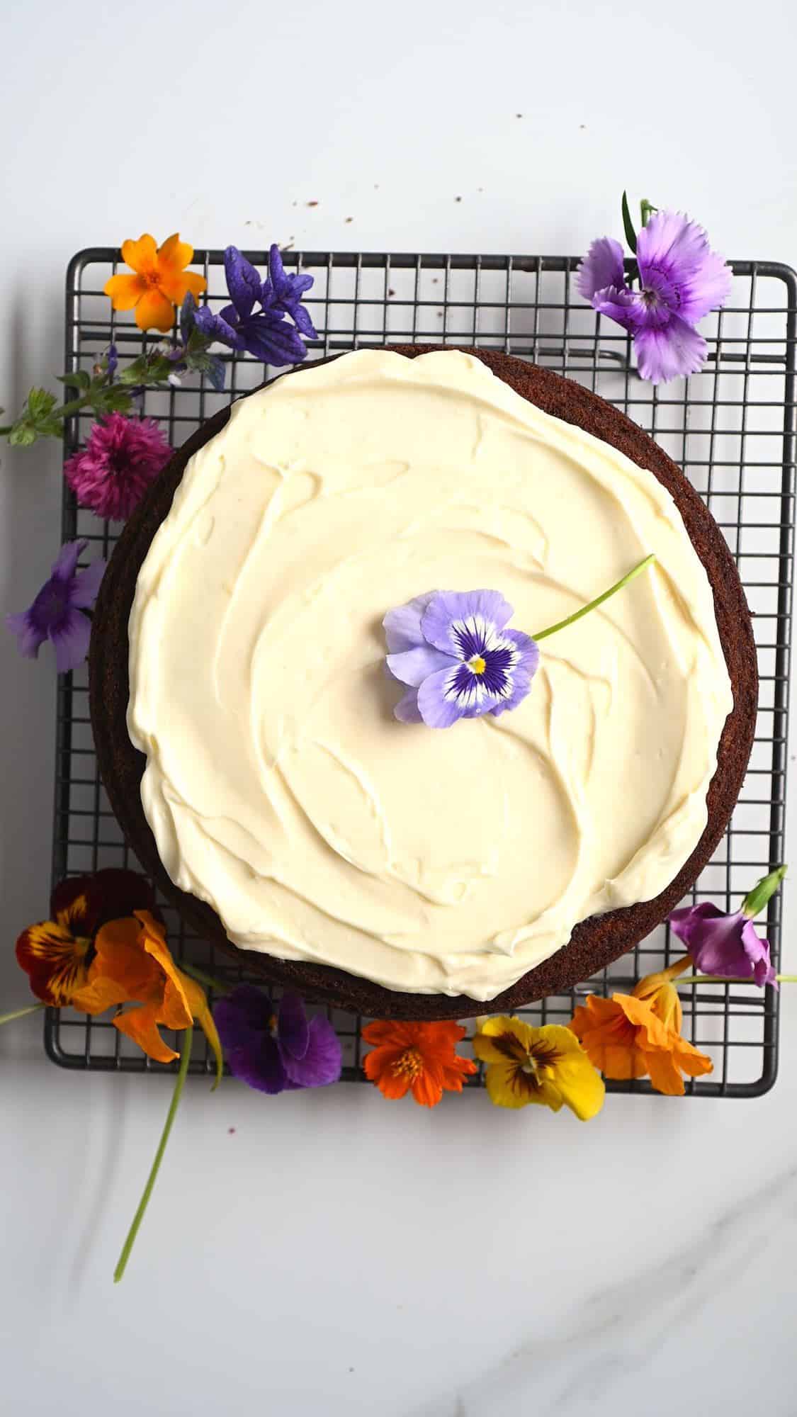 Frosted carrot cake and some edible flowers on and around it