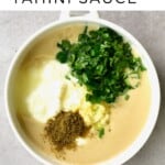 Tahini in a bowl with parsley yogurt and spices added on top