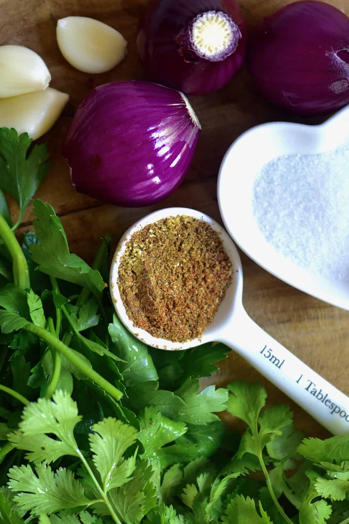 falafel spice mix in a small spoon next to parsley and onion