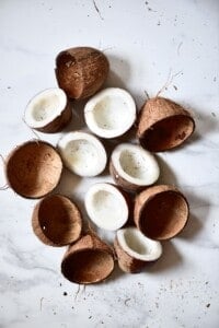 three coconuts cut in half with the flesh removed from the shells