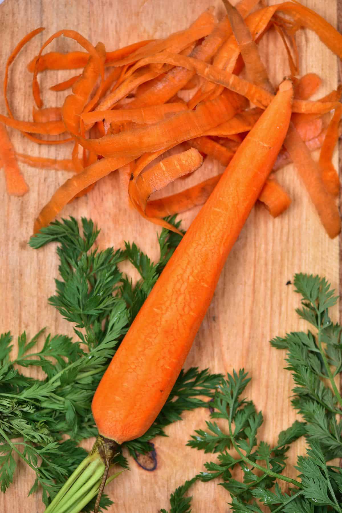 Peeled carrot on a chopping board with the peels next to it