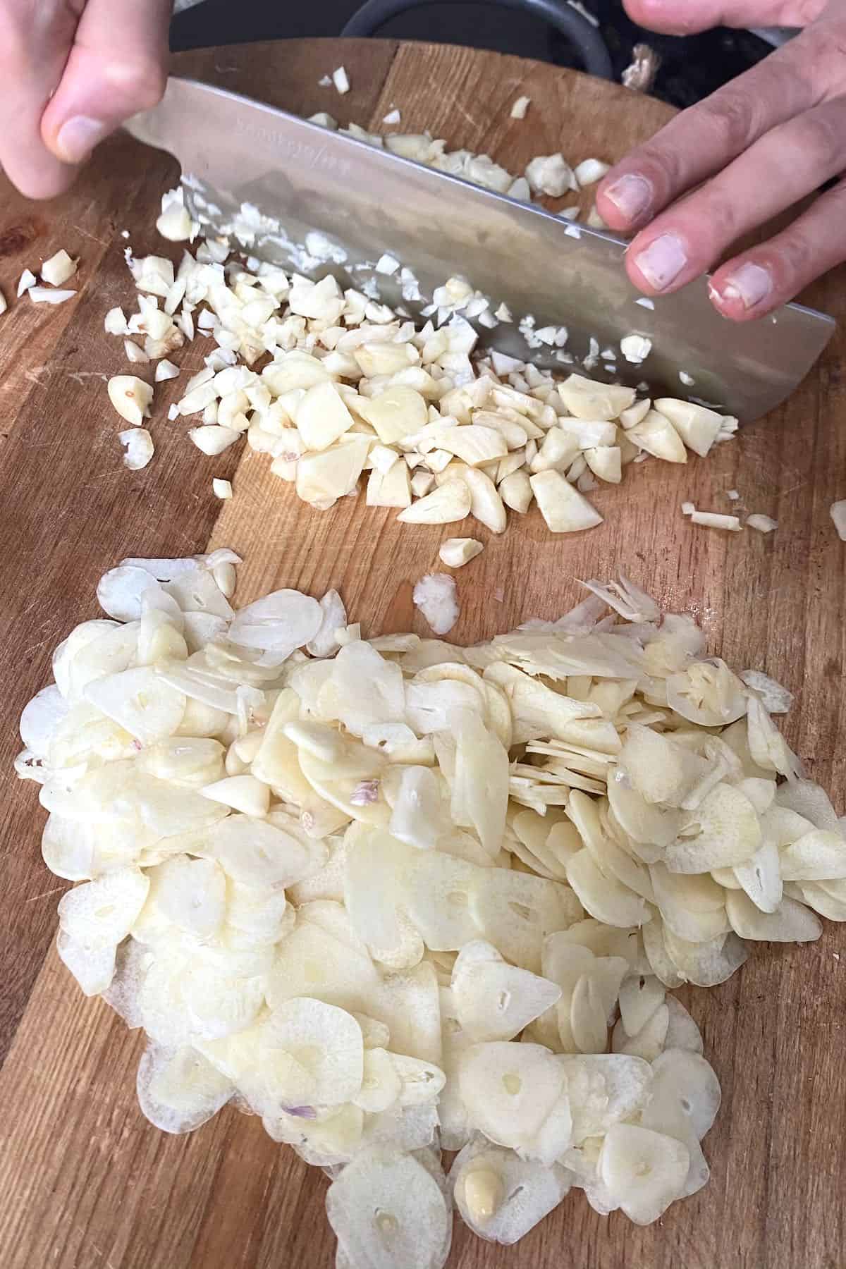Mincing garlic with a knife on a chopping board