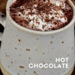 Hot chocolate topped with whipped cream and chocolate shavings in a cup
